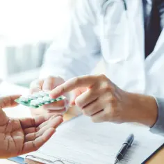 Lekarz podaje pacjentowi opakowanie tabletek, symbolizując moment, kiedy antybiotyk zaczyna działać i przynosi ulgę.